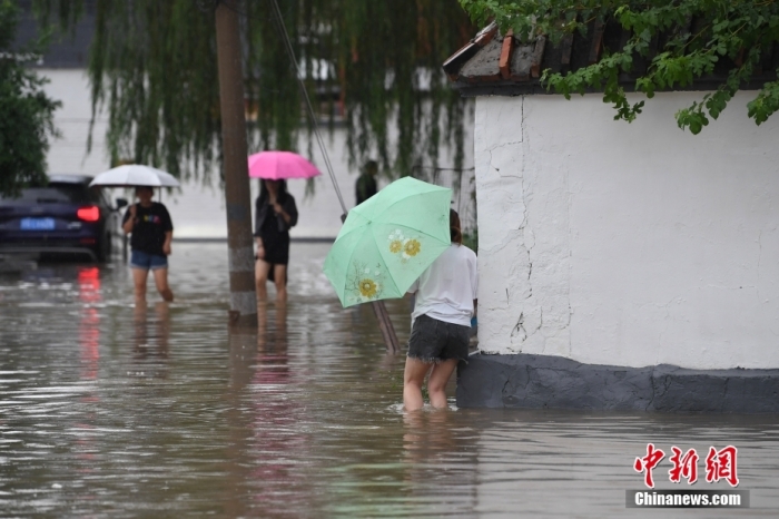 7月31日，市民行走在雨中的北京房山區(qū)瓦窯頭村。北京市氣象臺(tái)當(dāng)日10時(shí)發(fā)布分區(qū)域暴雨紅色預(yù)警信號(hào)。北京市水文總站發(fā)布洪水紅色預(yù)警，預(yù)計(jì)當(dāng)日12時(shí)至14時(shí)，房山區(qū)大石河流域?qū)⒊霈F(xiàn)紅色預(yù)警標(biāo)準(zhǔn)洪水。<a target='_blank' href='/'><p  align=