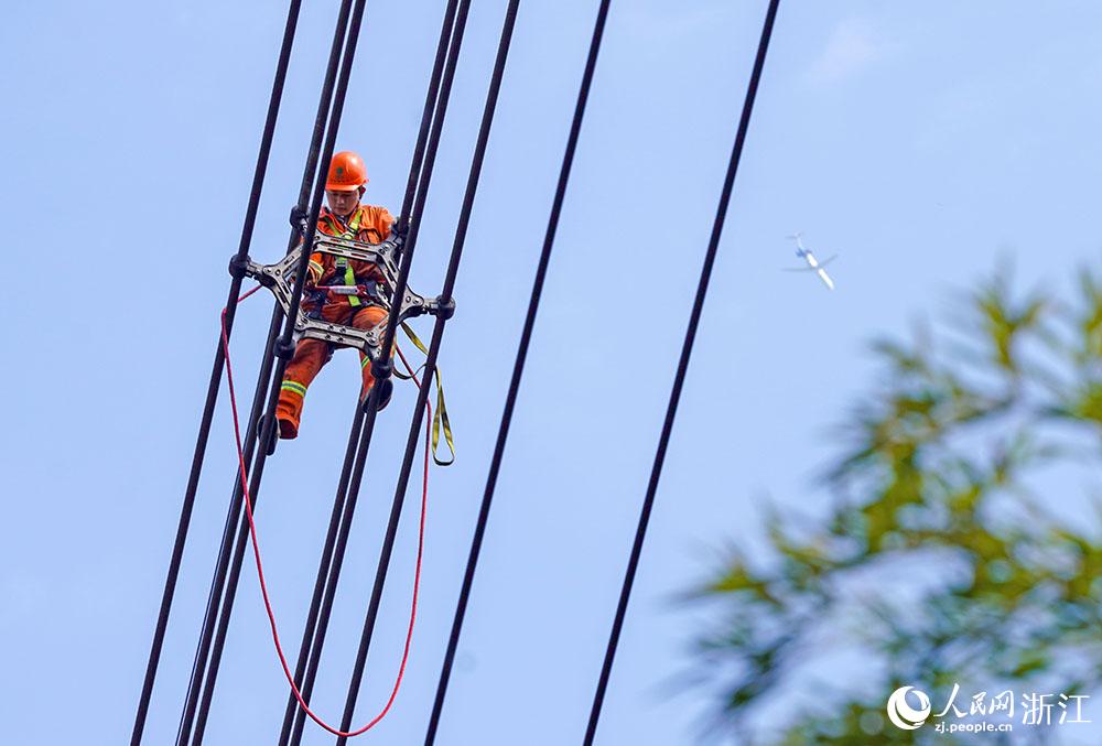 3月11日，在浙江省諸暨市河上鎮(zhèn)，浙江省送變電工程有限公司檢修人員在高空的導(dǎo)線上進(jìn)行線路檢修維護(hù)。人民網(wǎng) 章勇濤攝