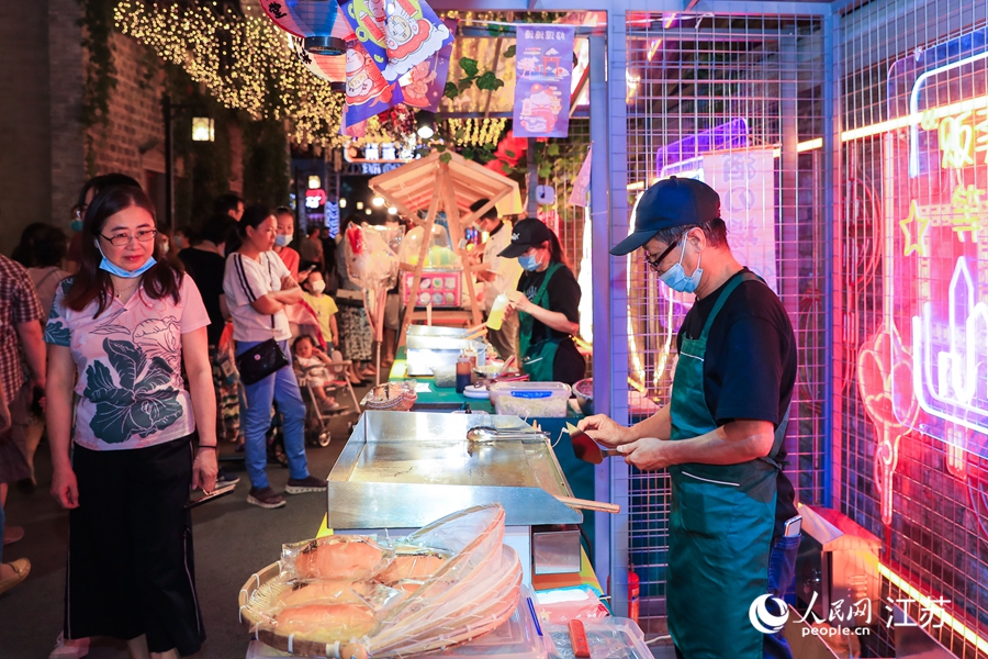 夜市老板正在準(zhǔn)備餐食。熙熙攝