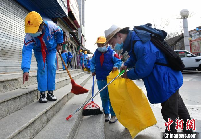 圖為拉薩市小學(xué)生打掃街道?！∝暩聛?lái)松 攝