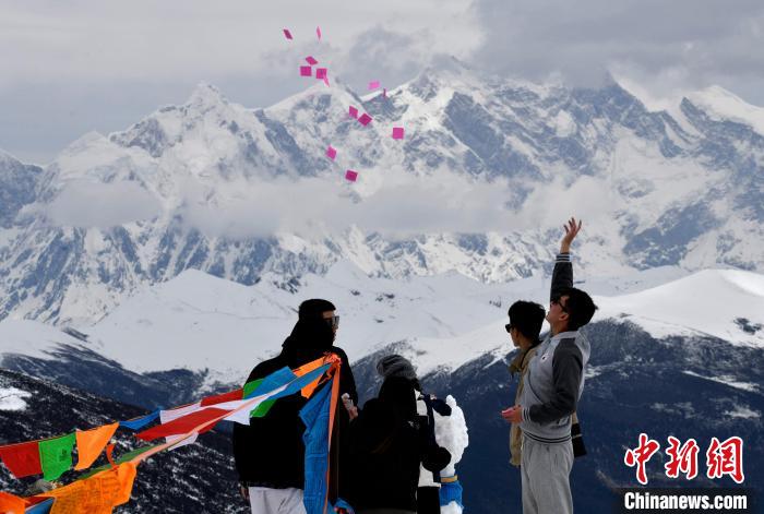 圖為5月14日，游客在西藏林芝色季拉山觀景臺拋灑“隆達”(風(fēng)馬旗，藏族民眾的一種祈福方式)?！±盍?攝