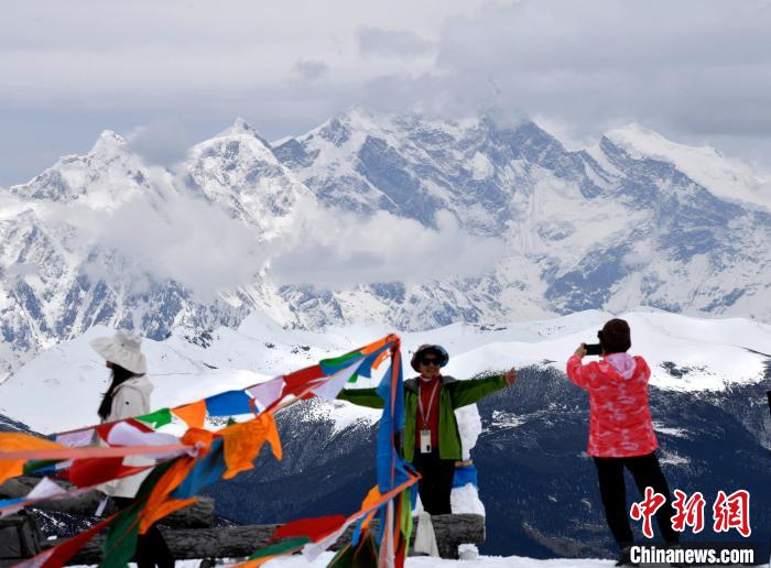 圖為5月14日，西藏林芝色季拉山觀景臺(tái)，游客與南迦巴瓦峰合影。　李林 攝