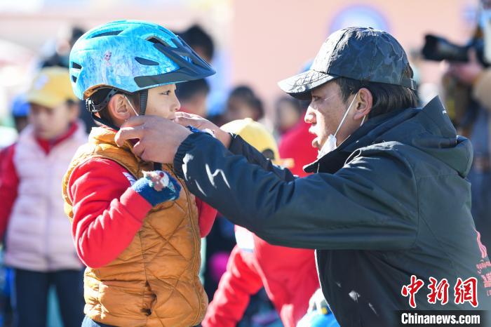 圖為拉薩市實(shí)驗(yàn)幼兒園孩子在教練的幫助下穿戴頭盔?！『闻罾?攝