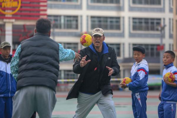 在高原上教孩子們打手球，“慢慢兒來(lái)，甭著急！”