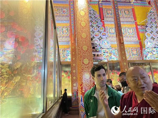 7月25日，省級(jí)非物質(zhì)文化遺產(chǎn)項(xiàng)目塔爾寺酥油花的代表性傳承人朋措堅(jiān)參（右）在塔爾寺酥油花館講解酥油花的制作過(guò)程。人民網(wǎng) 謝瑩攝