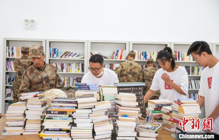 圖為志愿者們和邊防戰(zhàn)士整理圖書?！詵| 攝