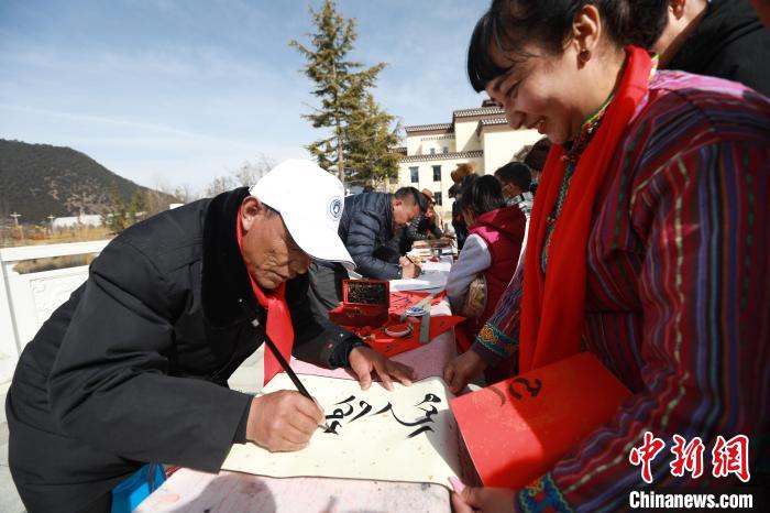 圖為林芝市文聯(lián)書法家協(xié)會(huì)會(huì)員向民眾贈(zèng)送藏文書法作品?！埩?攝